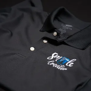 Black polo shirt with intricate custom embroidery on the chest, showcasing Iconic Prints' Custom apparel services.